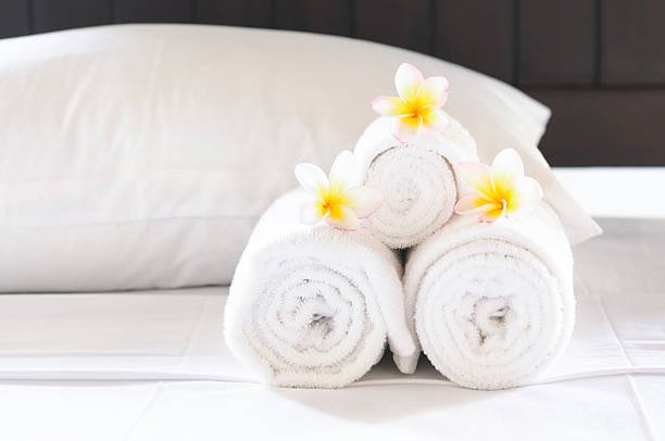Pillows, sheets and towels presented in a hotel.  Shallow depth of field.